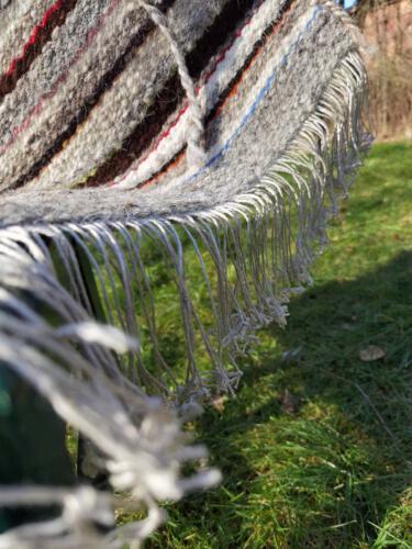 Die abgeschnittenen Kettfäden werden noch geknotet und zu einer Flechtkante verarbeitet